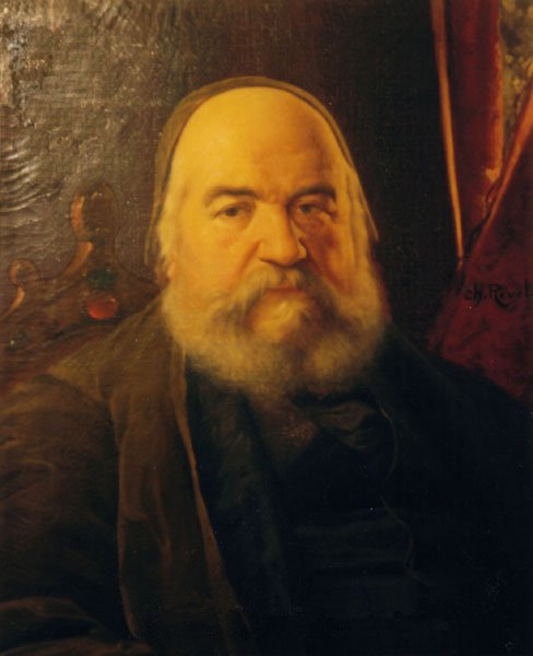 A classic 19th-century oil portrait of the French occultist Éliphas Lévi. He appears as an older man with a full, graying beard and mustache, warm brown eyes, and a bald head covered by a dark skullcap. He wears a dark coat and vest over a high collar. He rests comfortably against a carved wooden high-backed chair. The lighting softly illuminates his face from the left, while a rich red drapery hangs in the background on the right.