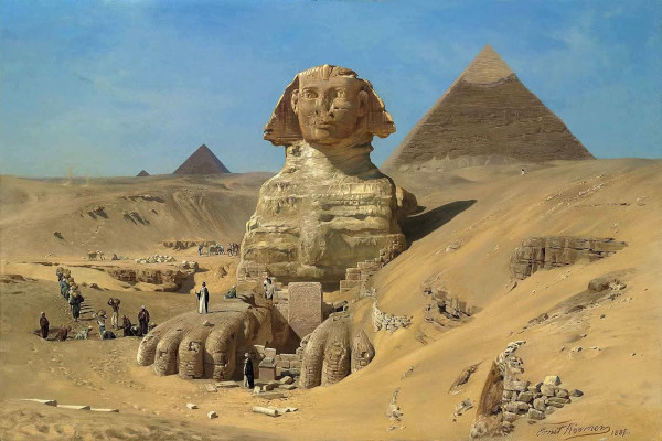 A romantic 19th-century oil painting of the Giza plateau at dusk. The stone Great Sphinx of Giza dominates the center foreground, its weathered face illuminated by a warm, golden sunset. In the background, the massive triangular silhouettes of the pyramids rise against a soft pink and orange sky. A small caravan of people and camels camps quietly in the shadows of the desert sands at the Sphinx's base.