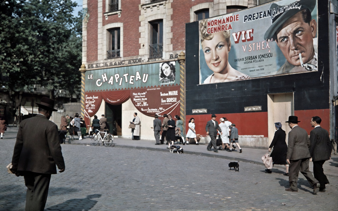 Color photograph of the exterior of Le Chapiteau at 1 Place Pigalle during the Occupation, featuring a circus-tent facade, pedestrians, and a large movie poster for the film "Vie de Bohème."