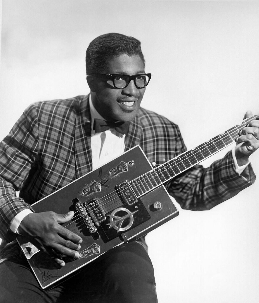 Historic publicity photograph of rock pioneer Bo Diddley holding his iconic rectangular electric guitar