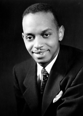 Historic black and white publicity headshot of the real composer and classical pianist Dr. Don Shirley in a dark suit and tie.